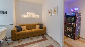 A modern room with a sofa, a neon sign, and a coin-operated game machine. - Vintage Apartment Giuliana (Rome)