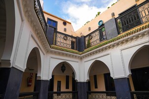 A courtyard with arches and balconies, featuring a fire extinguisher and a clock.