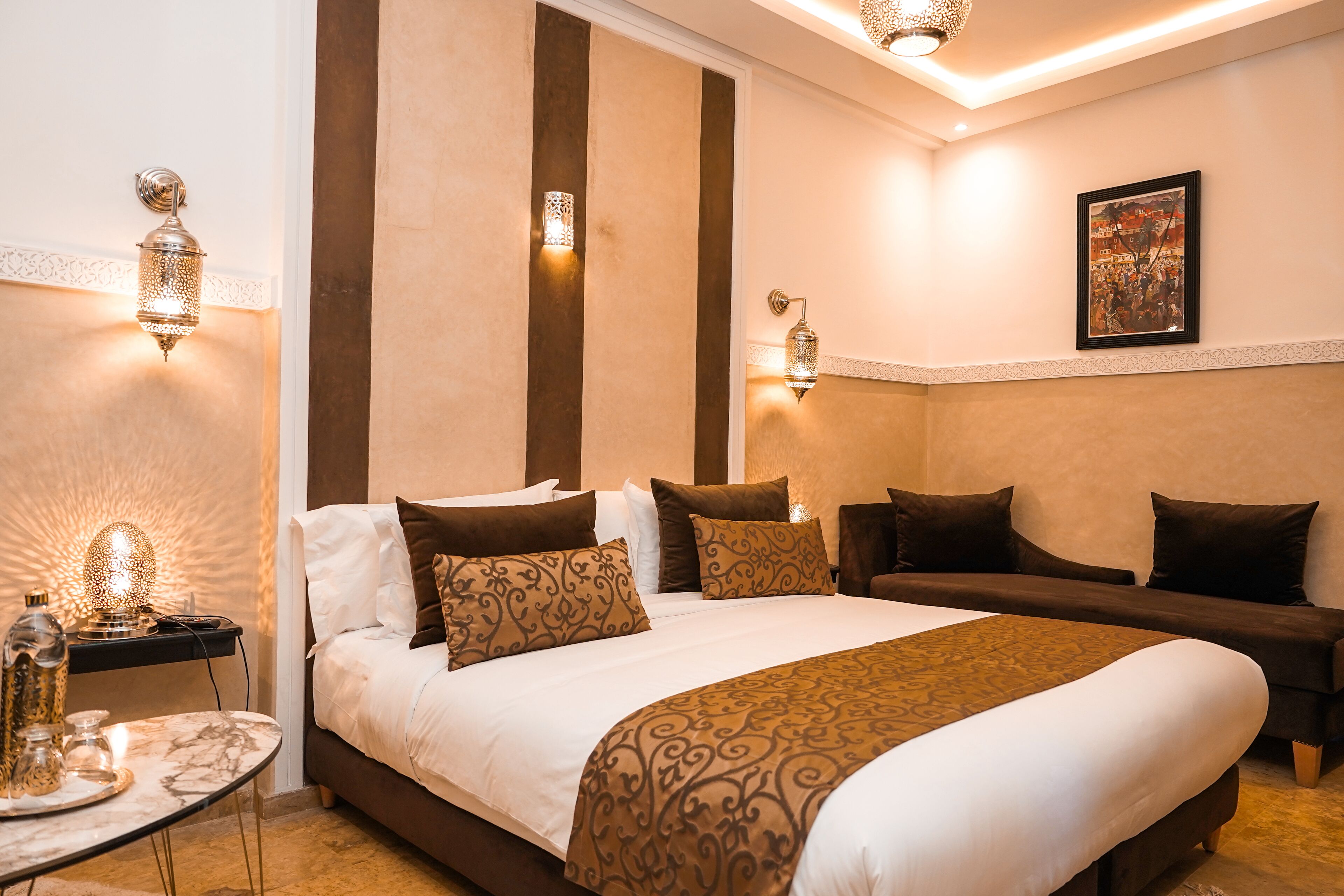 A hotel room with a large bed, two bedside tables, a wall-mounted lamp, and a framed picture.