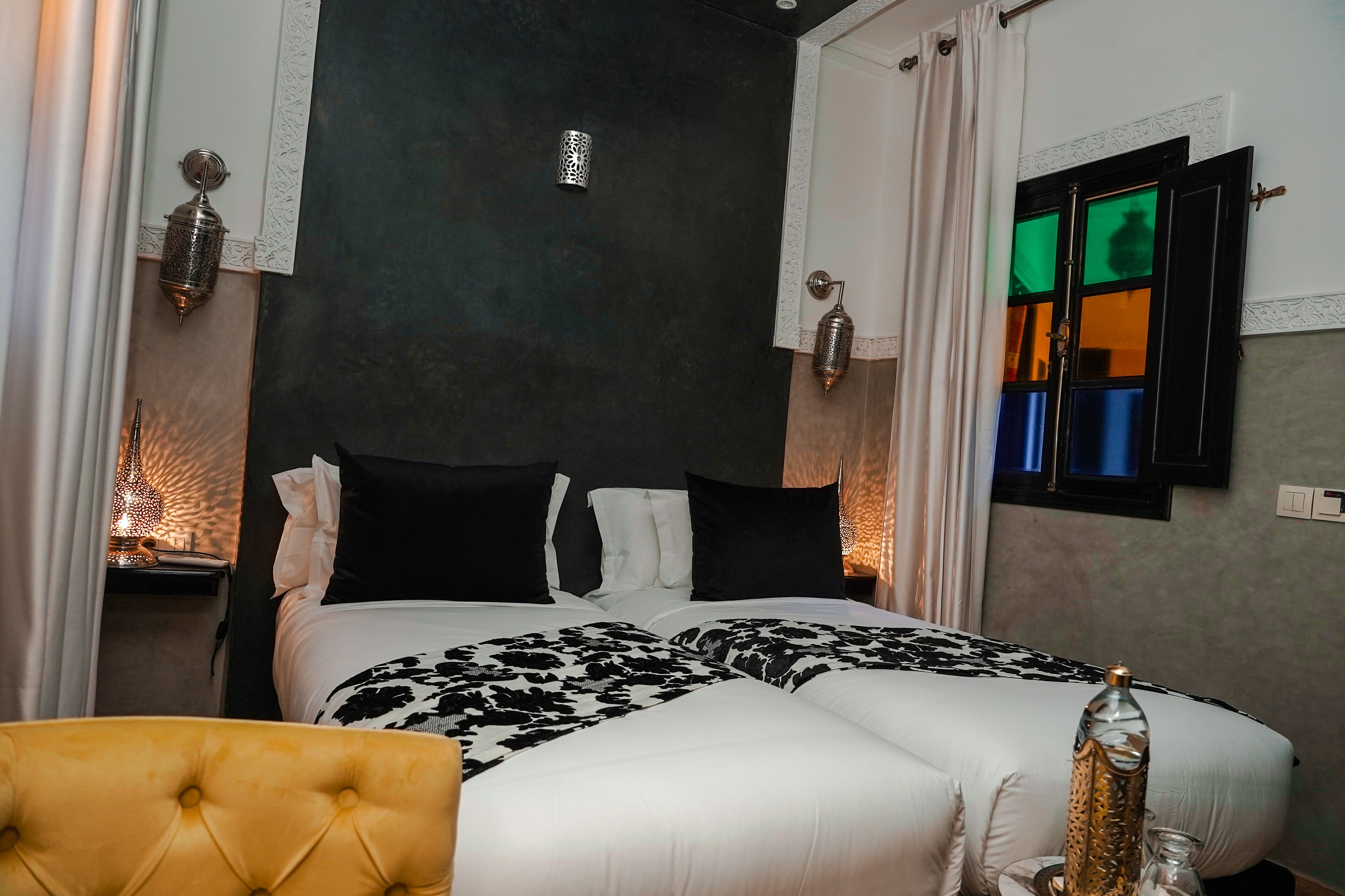 Ein Hotelzimmer mit einem großen Bett, einem gelben Sessel und dekorativen Wandleuchten.