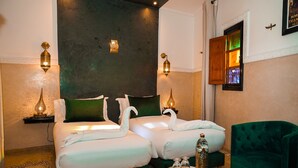 A room with two beds, a green armchair, and a small table with a tray. - Riad Roummana Marrakech (Marrakech)