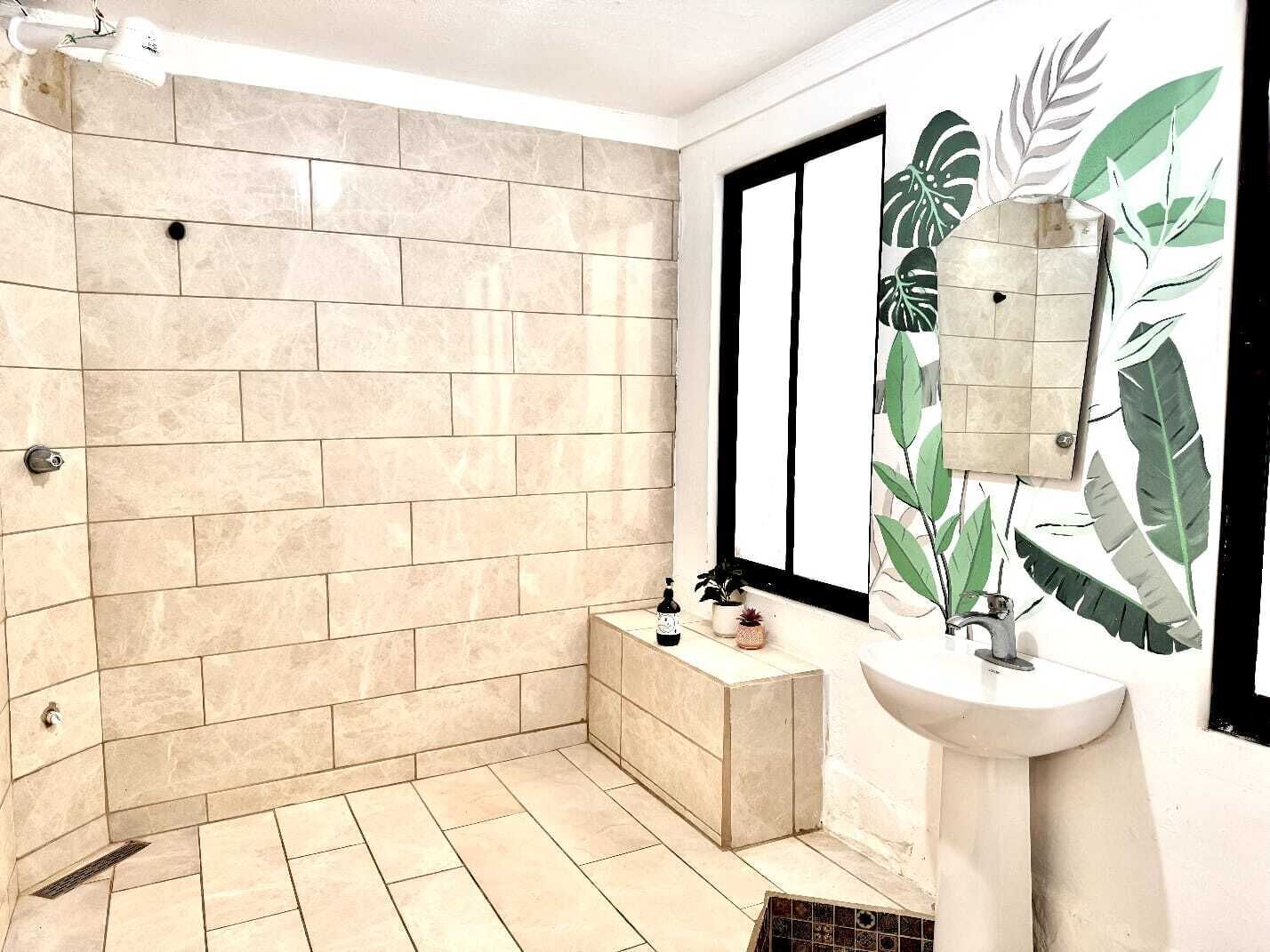 Un baño con piso de baldosas, lavamanos y zona de ducha.