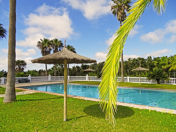 Una piscina al aire libre de temporada, sombrillas
