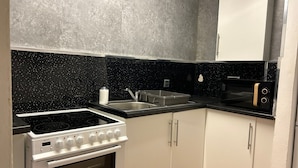 A kitchen with a black countertop, white cabinets, a stove, and a microwave. - VS-Entire Flat-Central Scotland-Falkirk| Self-Check-in |Pet-friendly | Parking (Falkirk)