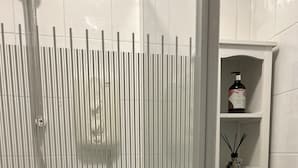 A bathroom with a shower enclosure featuring vertical blinds, a white tiled wall, a shelf with a bottle and a potted plant, and a cabinet with a door. - VS-Entire Flat-Central Scotland-Falkirk| Self-Check-in |Pet-friendly | Parking (Falkirk)