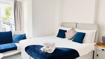 A hotel room with a bed, a chair, a small table, and a nightstand.