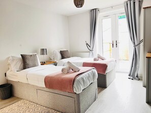 Habitación de hotel con dos camas, una mesita, una lámpara y vistas al exterior.
