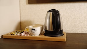 Una cafetera sobre una bandeja de madera con una taza que dice 'NEW KONAK HOTEL' y algunos paquetes de té.