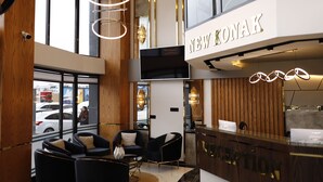 Un interior moderno con un mostrador de recepción que dice "NEW KONAK" y una zona de estar con dos sillones y un sofá.