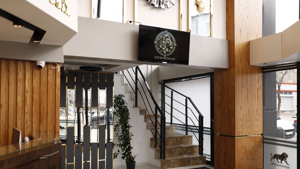 Un interior moderno con una mesa de recepción, una escalera y un cartel que dice 'NEW KONAK'.