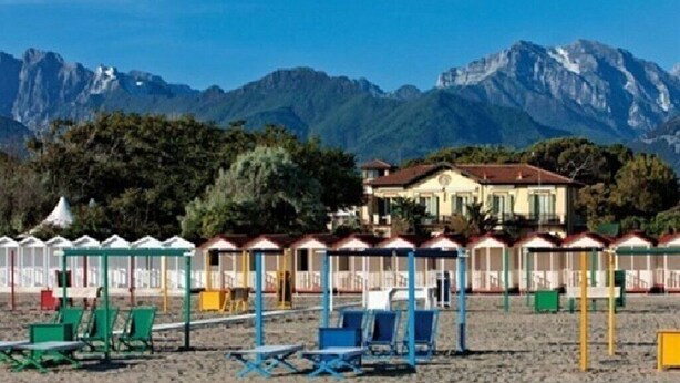 A beach with beach huts and a mountain backdrop. - Cozy and comfort Villa in the Lucca surroundings (Capannori)