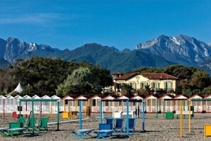 Ein Strand mit Strandhütten und einer Bergkulisse.