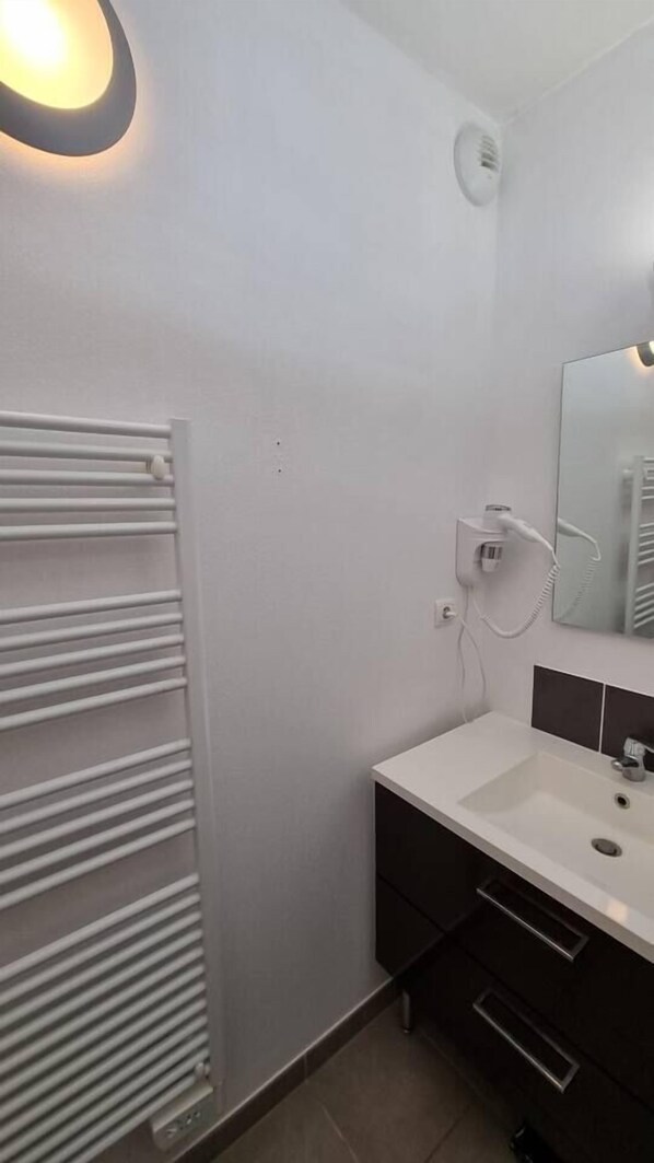 A modern bathroom with a white radiator, a white sink, and a mirror.