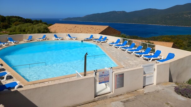 Una piscina con sillas azules y vista al mar.