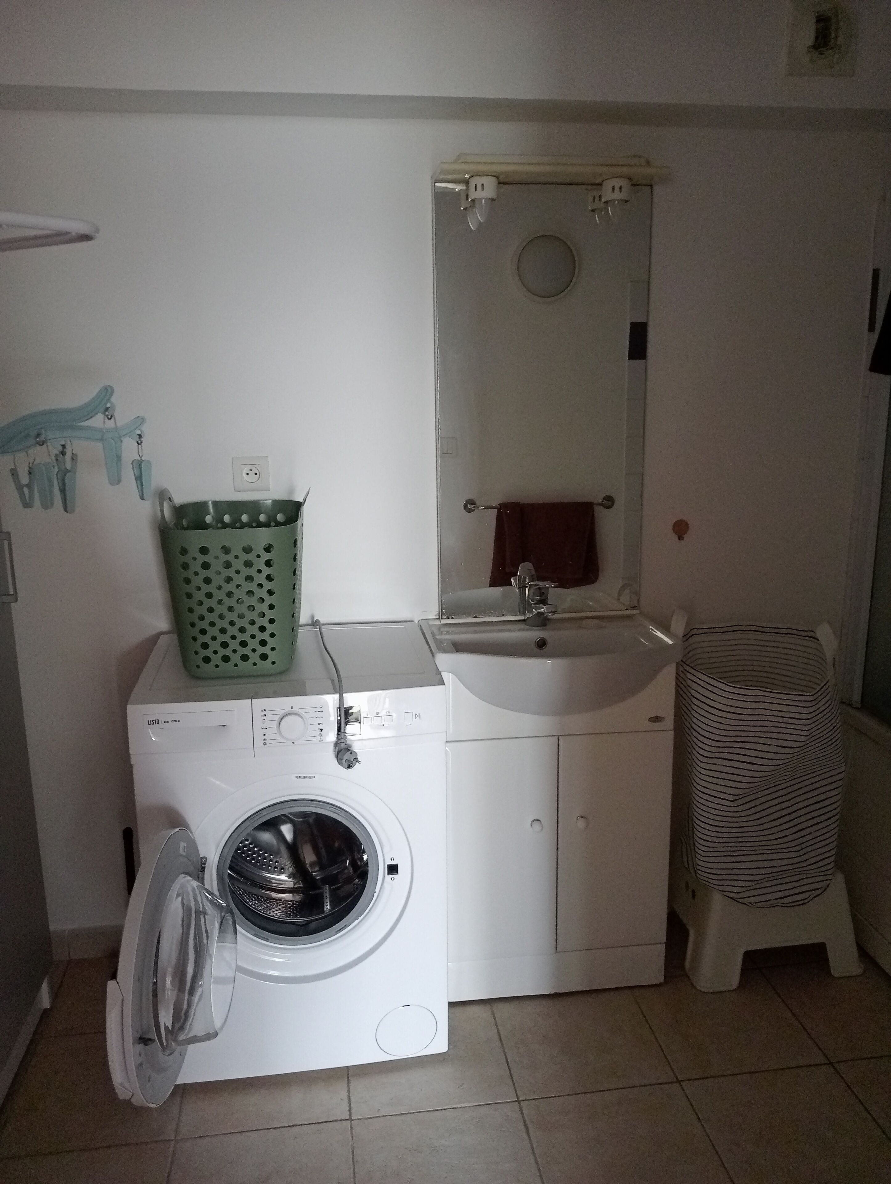Een praktische wasruimte met een wasmachine, een spoelbak en een klein krukje.