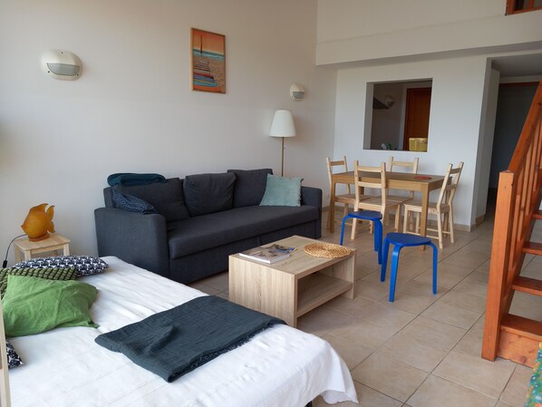 A modern living room with a sofa, a coffee table, a bed, and a dining area with chairs and a table. - Appartement vue Mer- 6 Places- Piscine (Serra di Ferro)