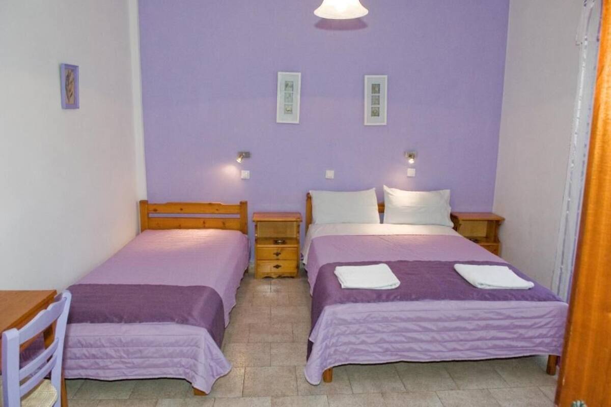 Habitación doble con dos camas, cabeceros de madera, mesitas de noche e iluminación de pared.