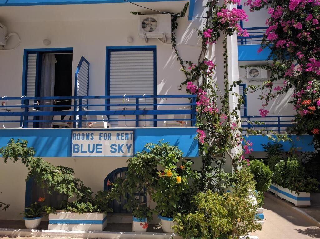 A building with a sign reading "Rooms for Rent Blue Sky."