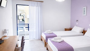 Een hotelkamer met twee eenpersoonsbedden, een houten bureau, een stoel en een kleine tafel met een lamp.