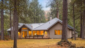 Une cabane dotée d’une grande véranda, de nombreuses fenêtres et d’une cheminée.
