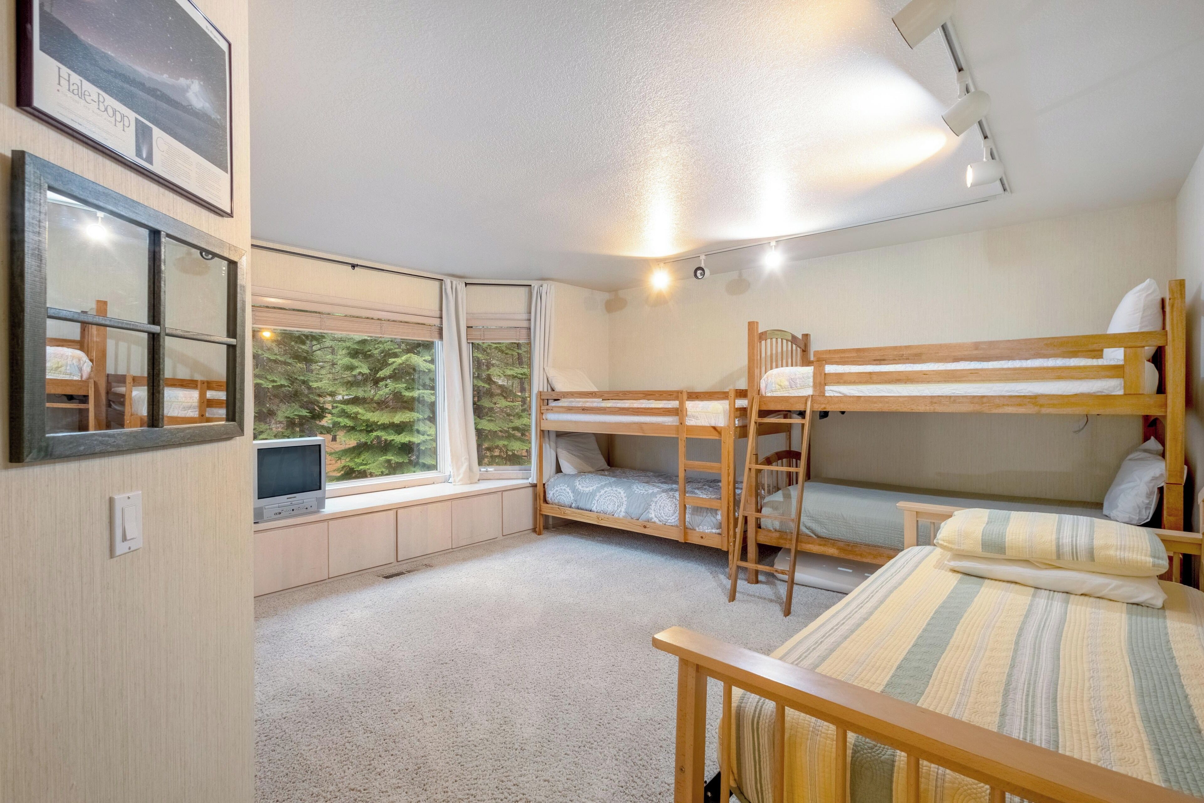 A bunk bed room with a window, a desk, and a mirror.