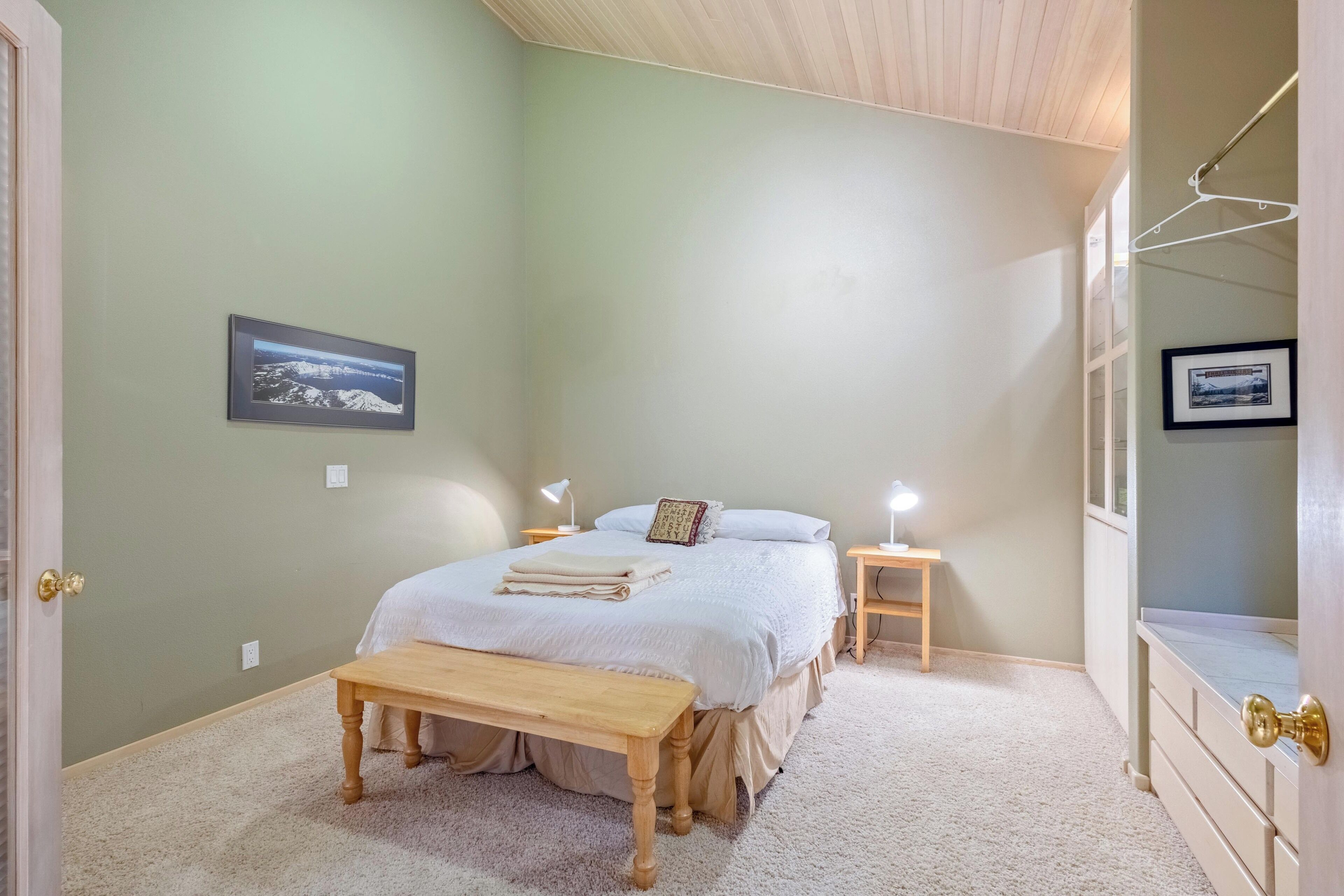 A bedroom with a bed, bedside tables, a bench, and a dresser.