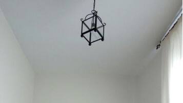 A bedroom with a bed, a hanging light fixture, a nightstand, and a wall-mounted picture.