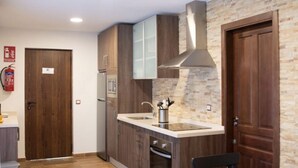 A compact kitchen with wooden cabinets, a stainless steel range hood, a built-in oven, and a stone backsplash. - Lagar del Chorro junto Caminito del Rey (Álora)