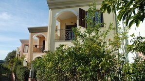 A two-story residential building with a balcony, surrounded by greenery. - Holiday home (Villasimius)