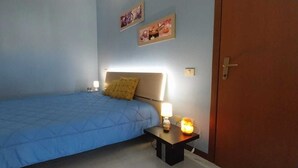 A bedroom with a single bed, a nightstand with a lamp, and a door. - Holiday home (Villasimius)