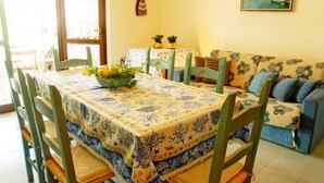 A dining area with a table set for two, a sofa, and a painting on the wall. - Holiday home (Villasimius)