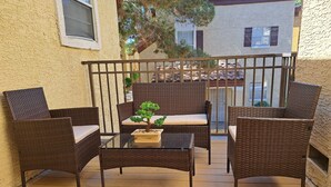 Un balcon agrémenté de meubles en osier, d’une petite table et d’une plante en pot.