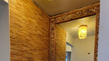 Ein Badezimmer mit einer Holzwand, einem Waschbecken mit Natursteinbecken und einem Spiegel mit dekorativem Rahmen.