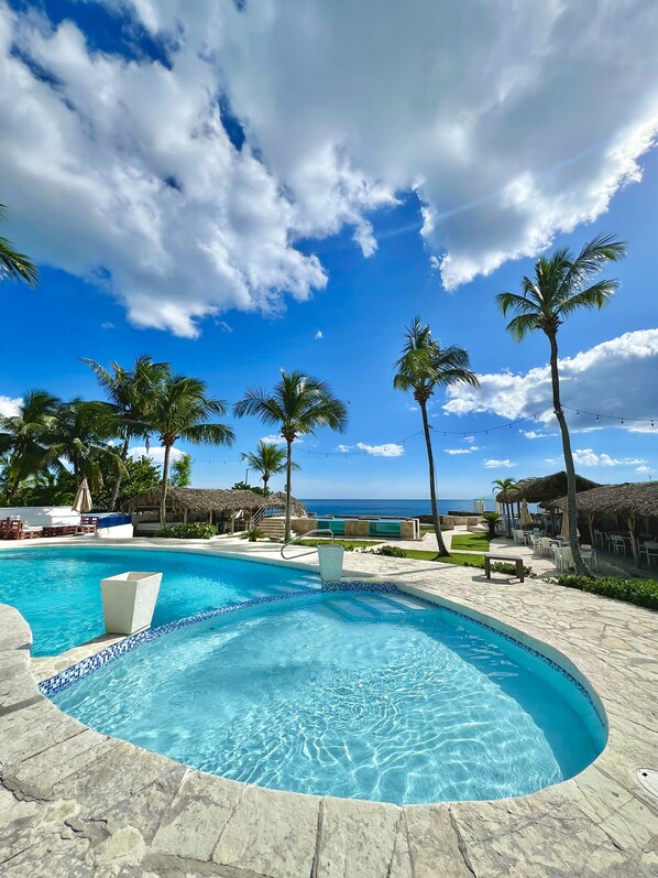 Relax by the resort pool surrounded by palm trees and ocean views.