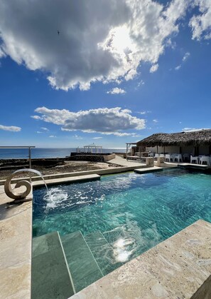 A clear blue sky with a pool area, a thatched-roof structure, and a gazebo.