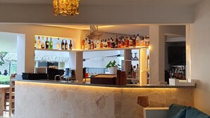 Un espace bar avec un sol en pierre, un canapé avec des coussins et un luminaire au plafond.