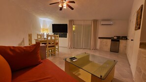 Cozy living space with a glass-top coffee table, dining table, and flat-screen TV.