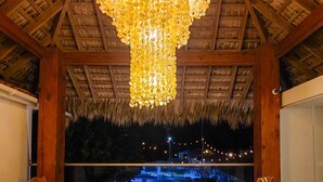 Un salon confortable, agrémenté d’un grand lustre, de meubles en bois et offrant une vue sur un élément décoratif aquatique illuminé la nuit.