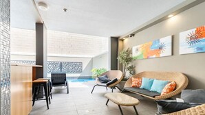 A modern outdoor seating area with wicker furniture, a pool, and artwork on the walls.