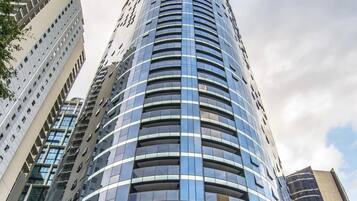 A tall, modern hotel with a curved entrance and a prominent address sign.