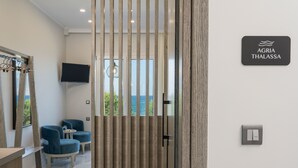 A modern room with a large window, a TV, and a sign that reads "AGRIA THALASSA". - Alexia Seaview Apartments (Kissamos)