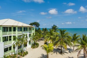 A resort with a beach view, multiple floors, and palm trees. - Beach Walkout Condo 112 3BR/2BA Sleeps 8 (Placencia)