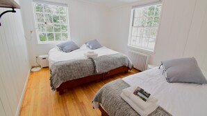 A room with two beds, wooden flooring, white walls, and large windows. - Le Partage Lodge (Val Morin)