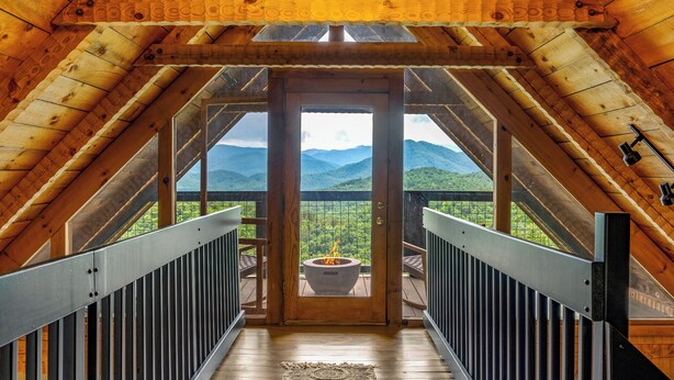 A wooden interior with a balcony overlooking a mountainous landscape.