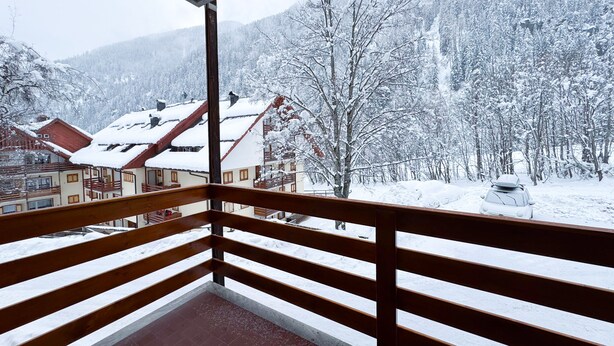 En balkon med udsigt til et sneklædt bjerg og en bygning med røde tage.