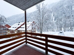 Ein Balkon mit Blick auf einen schneebedeckten Berg und ein Gebäude mit roten Dächern.