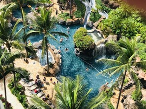 A resort pool area with multiple water features, palm trees, and lounge chairs. - Waikiki | Beach & Lagoon | Resort Pools | Studio (Honolulu Oahu)