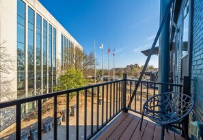 A balcony with a view of a building, flags, and a clear sky.