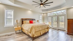 A bedroom with a large bed, a ceiling fan, and a view of the outdoors through a sliding glass door. - Spacious Hampton Vacation Home Near Beaches! (Hampton)
