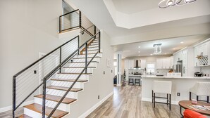 A modern kitchen with white cabinets, a central island, and a dining area with a red chair. - Spacious Hampton Vacation Home Near Beaches! (Hampton)